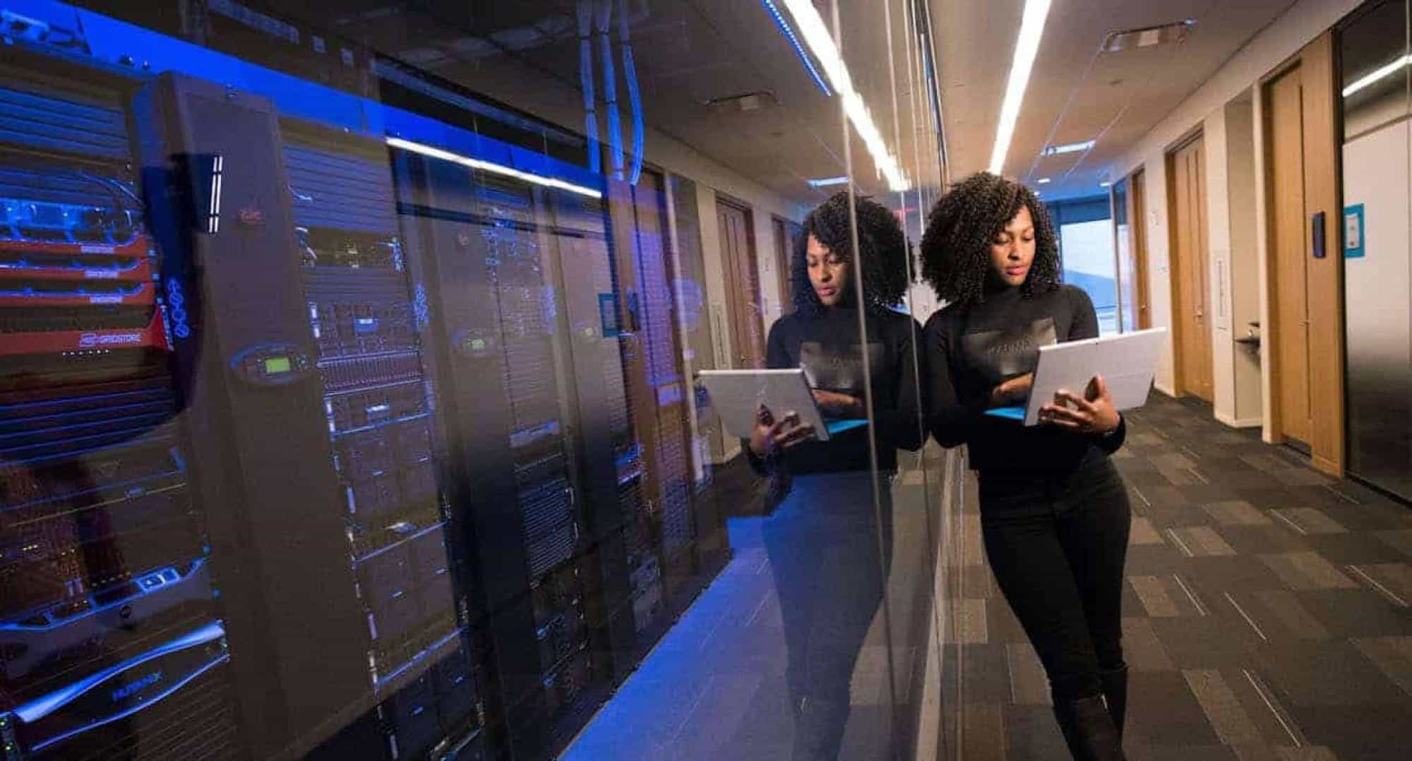Female developers working with tablets in a high-tech data center corridor.